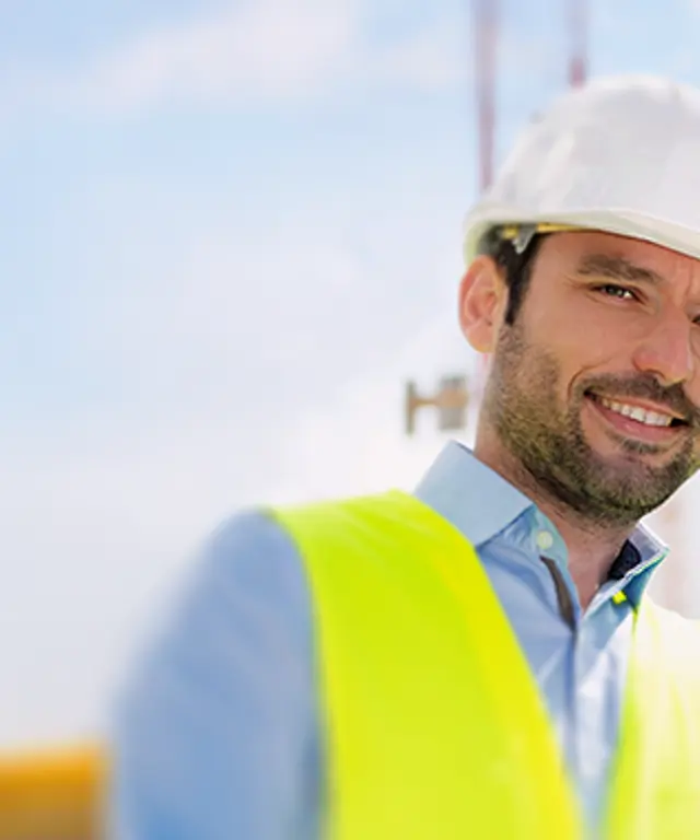 Zwei Fachkräfte mit Warnwesten stehen auf einer Baustelle. Symbolbild für Bauprojekte, Zusammenarbeit und sicheres Arbeiten im Außenbereich.