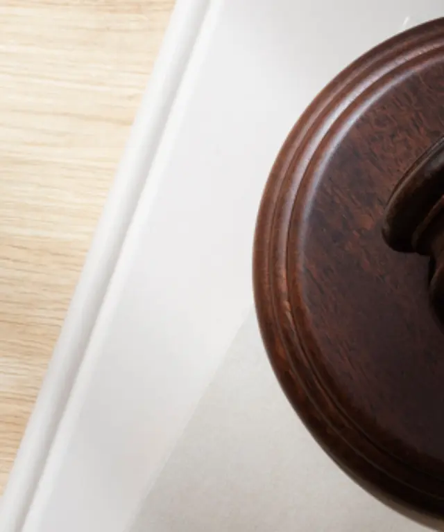 Holzrichterhammer mit goldfarbenem Band auf heller Unterlage – Symbol für Rechtsprechung, Gerichtsbarkeit und juristische Entscheidungen.