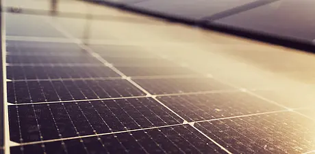 Mehrere Solarpaneele auf dem Dach eines modernen Gebaeudes, Himmel mit Wolken im Hintergrund